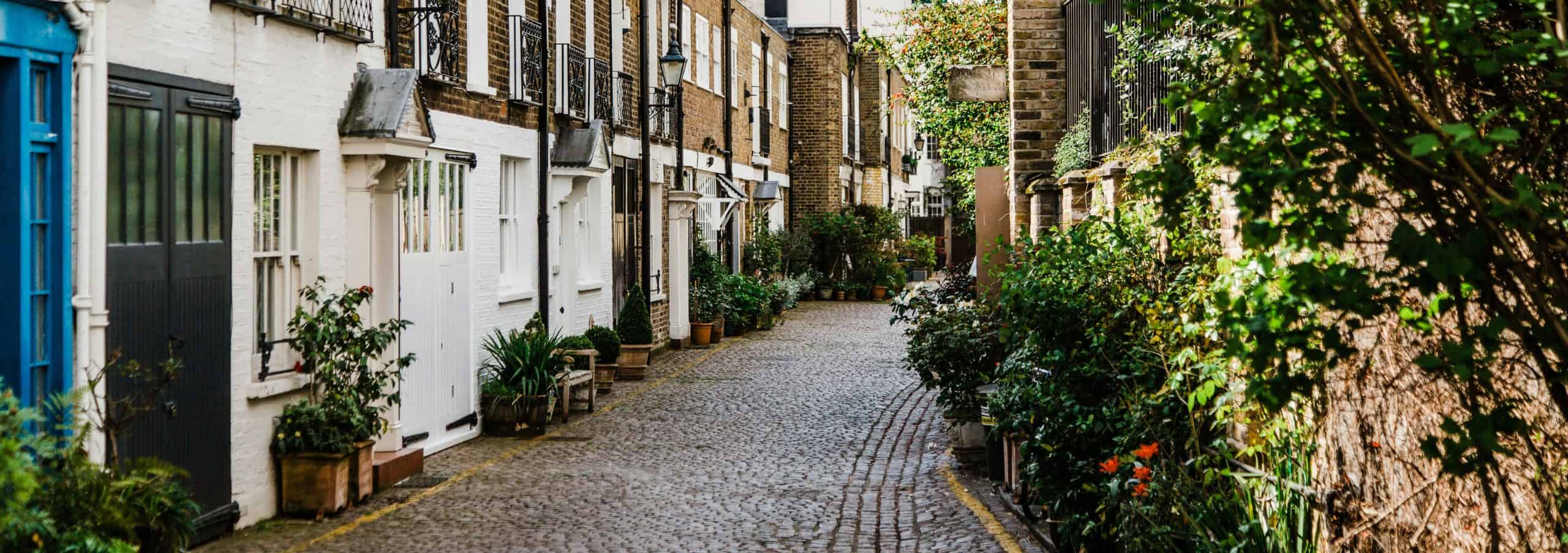 Cobbled mews street in London with greenery and residential buildings