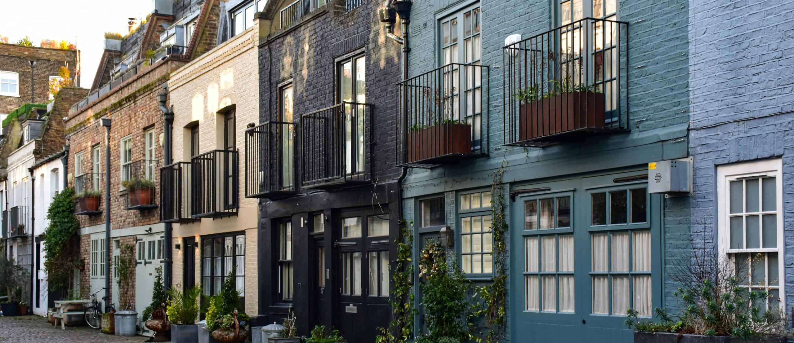 A row of UK-style townhouses with balconies and cobblestone street